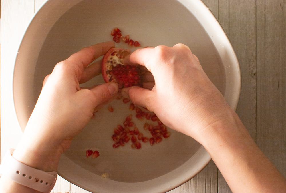 peeling pomegranate seeds in a bowl of water