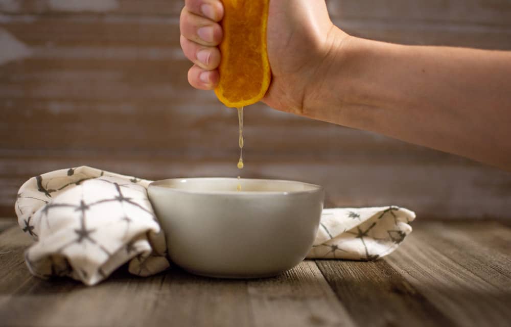 Hand squeezing orange juice into a bowl