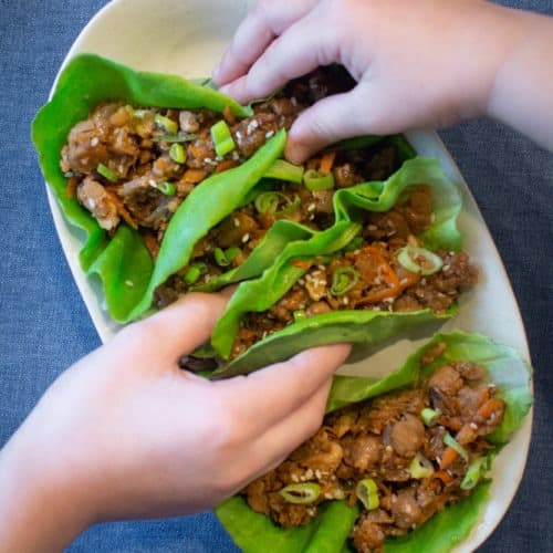Hands grabbing lettuce wraps off of serving platter