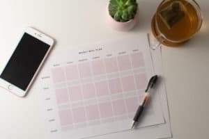 meal planning template flatlay with phone, pen, and cup of tea