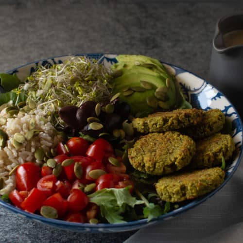 Bowl of salad next to container of dressing