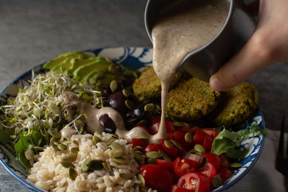 hand pouring dressing onto salad