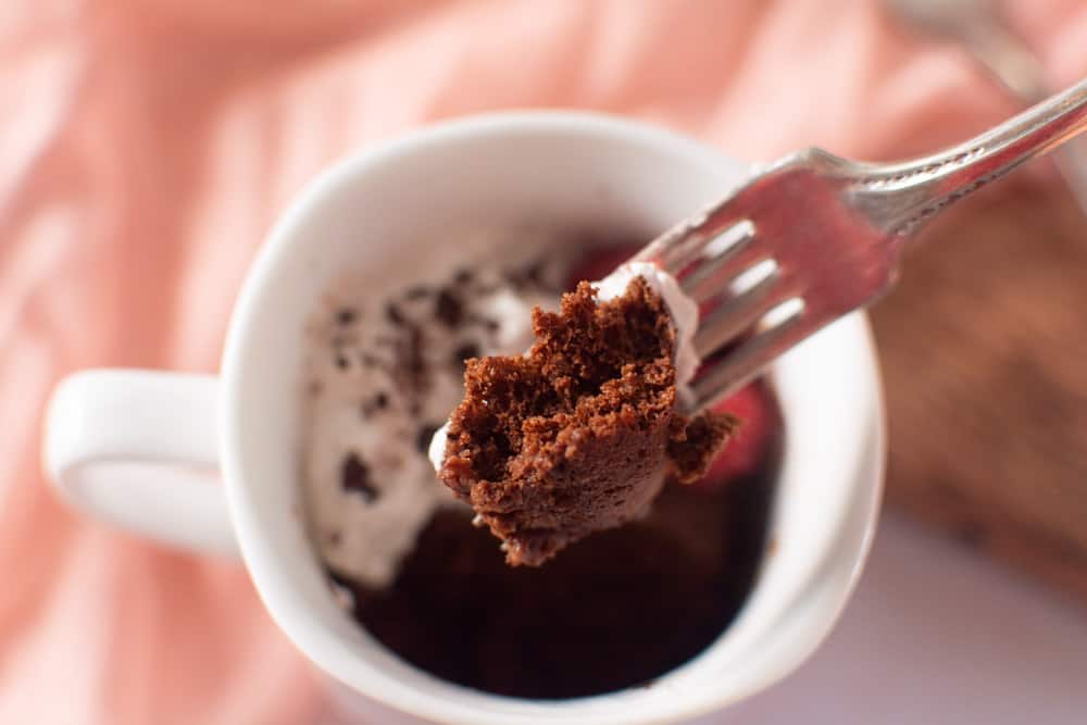 fork full of cake above mug