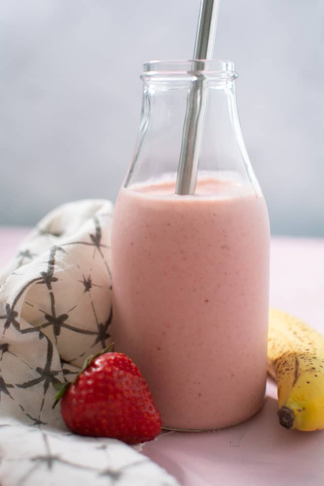 Pink smoothie in glass with metal straw