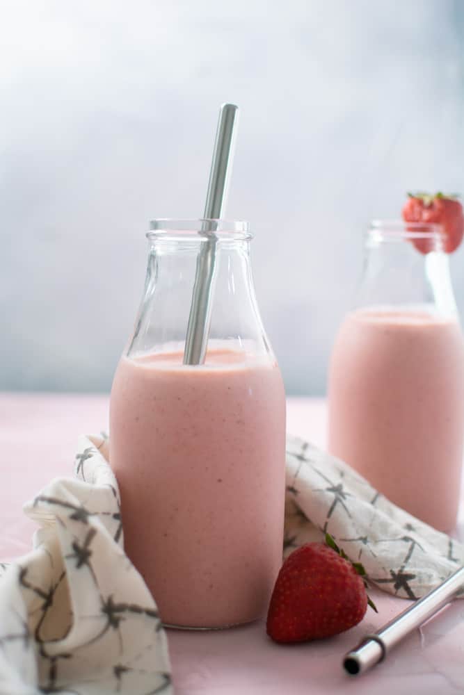 Two glasses of pink strawberry banana smoothie with almond milk