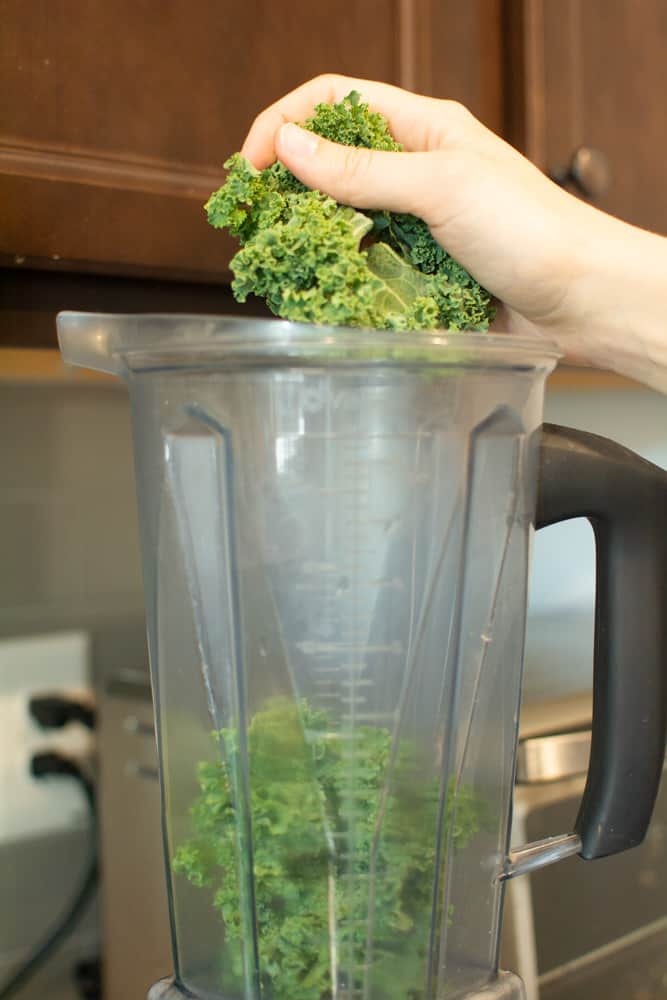 hand dropping kale into blender