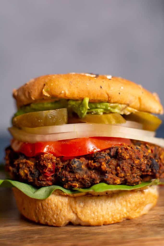 burger with black bean patty, lettuce, tomato, onion, pickles, and avocado