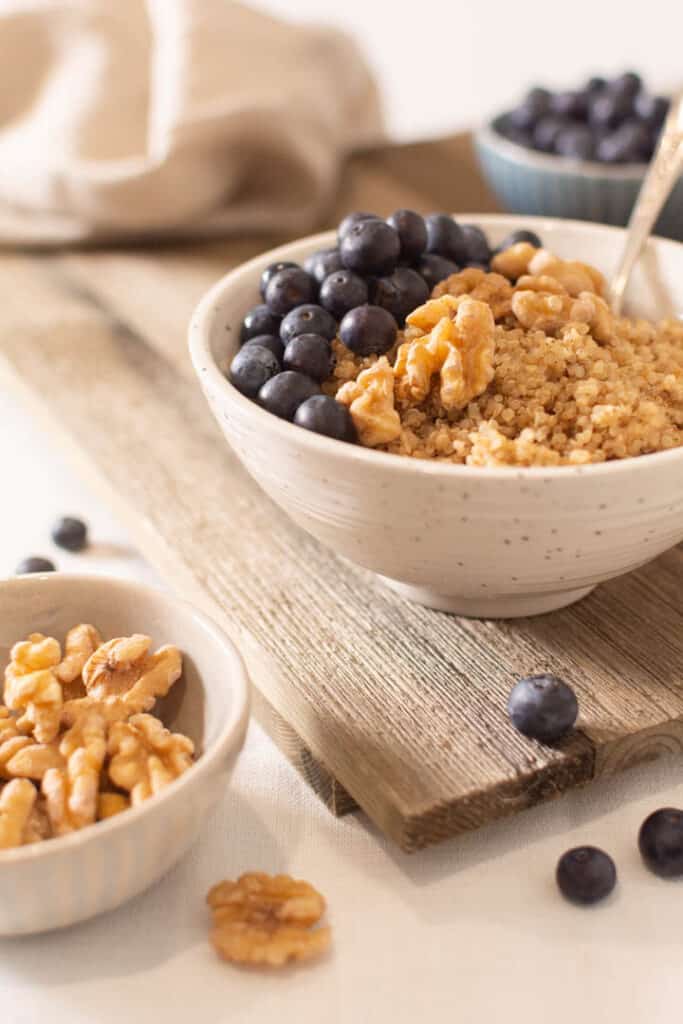 Quinoa porridge in bowl topped with fresh blueberries and walnuts