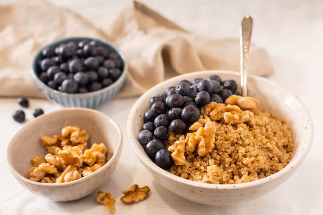 Quinoa porridge in bowl topped with blueberries and walnuts