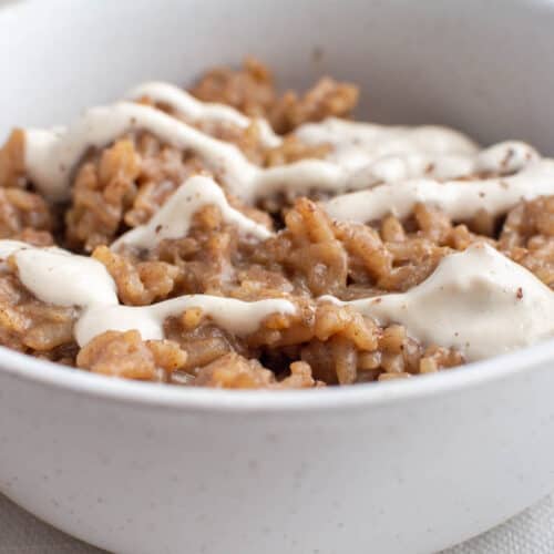 Rice pudding with white cashew cream on top in white bowl