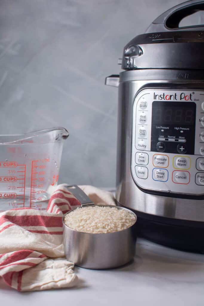 instant pot with 1 measuring cup of dry white rice and 1.5 cups of water