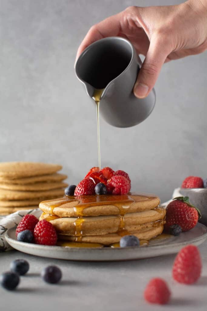 Pouring syrup over stack of pancakes