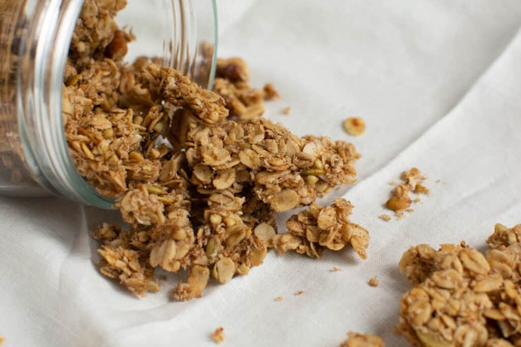 jar of granola spilling onto kitchen bowl