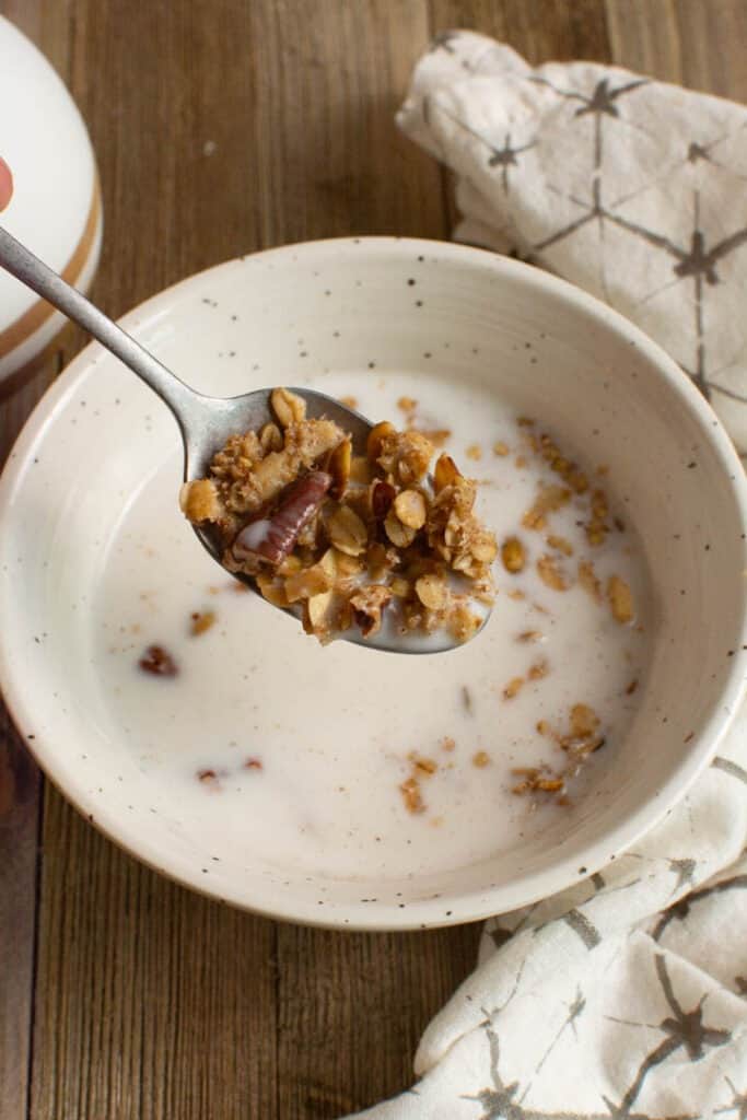 Someone spooning granola with milk out of bowl