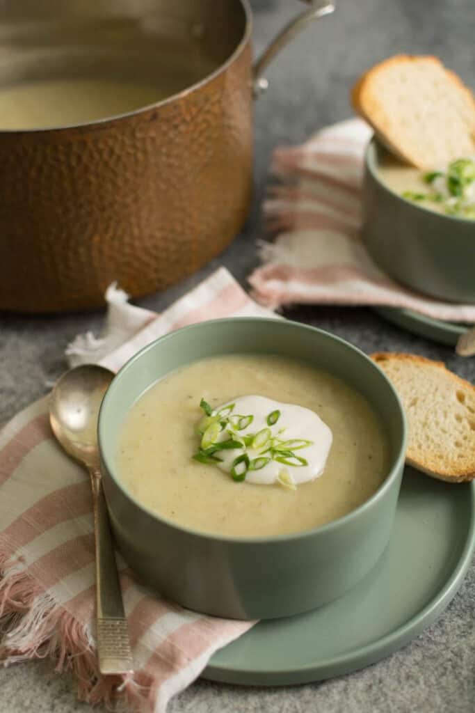 two bowls of soup with slices of bread, copper pot in the background