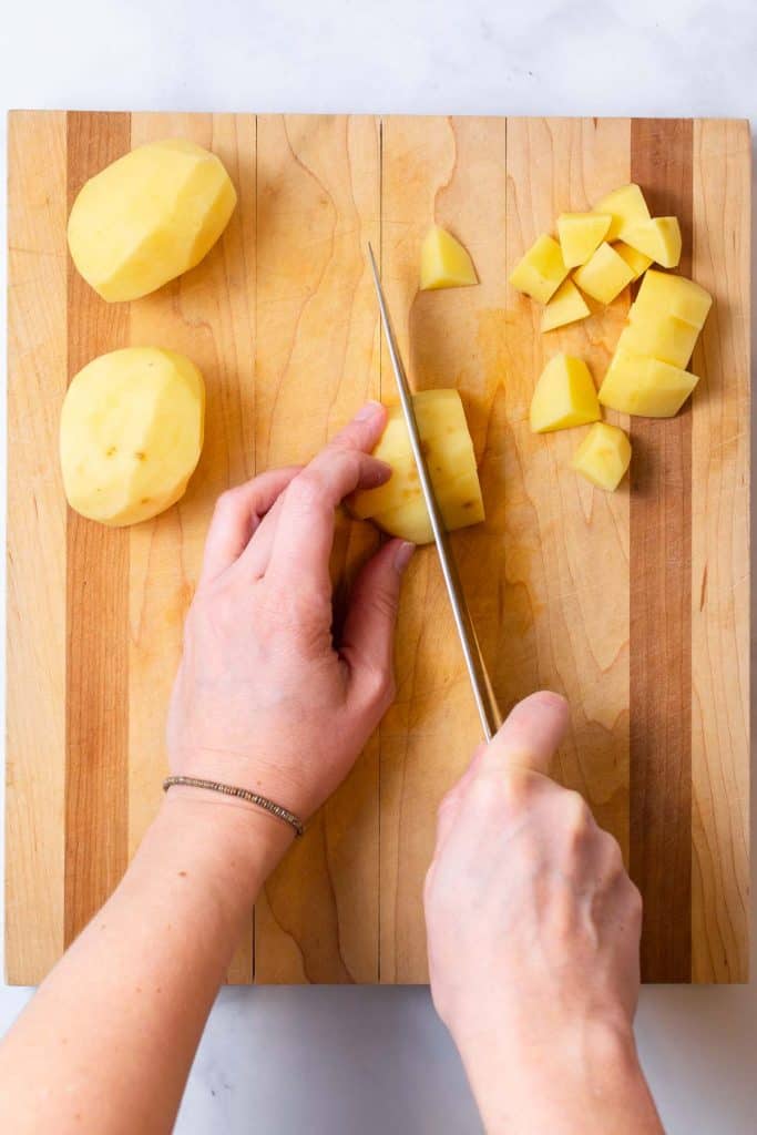 Cutting potatoes on chopping block.