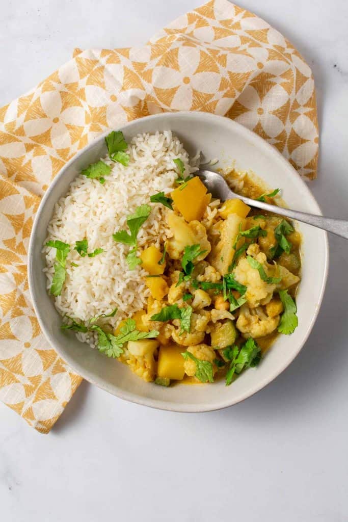 Birds eye view of curry and rice in a bowl garnished with parsley. 