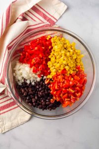 Bowl with black beans, onion, red pepper, corn, and diced tomatoes.