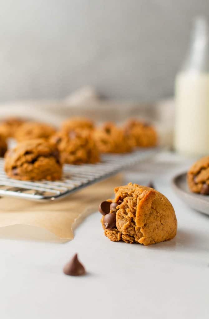 Peanut butter chocolate chip cookie with milk and extra cookies in the background.