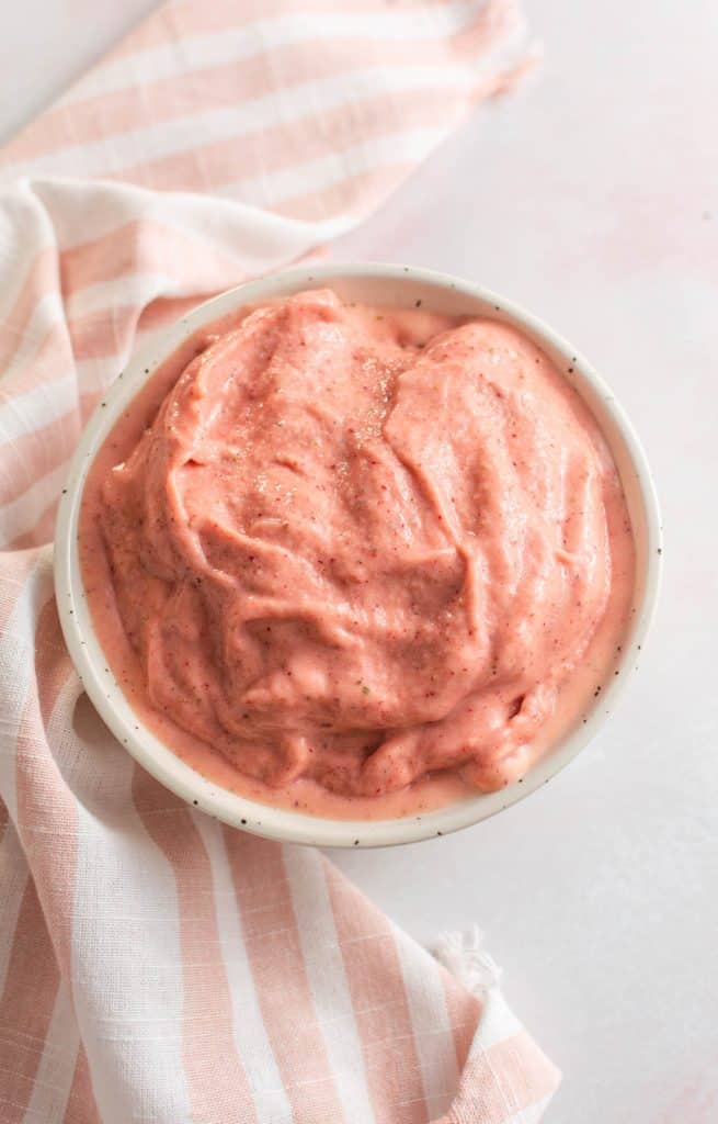 Smoothie in the bowl without any toppings and pink and white napkin on table.