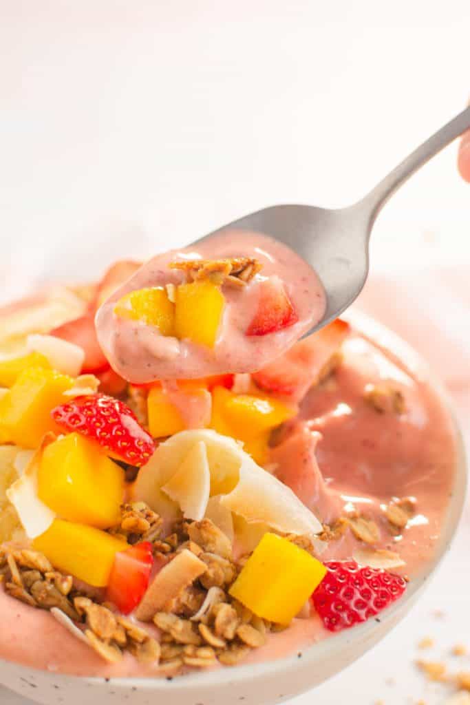 A spoon showing a bite of the smoothie bowl with some of the toppings.