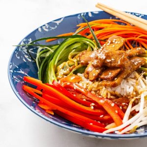 Close up shot of asian buddha bowl in a blue dish with chopsticks.