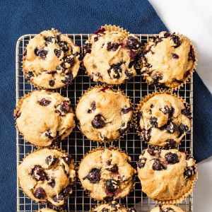 Overhead shot of 12 muffins on a cooling rack on a blue napkin.