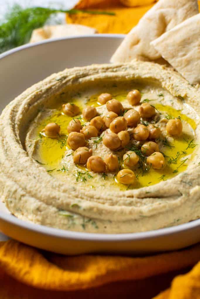 Close up of hummus being served on a plate with pita bread