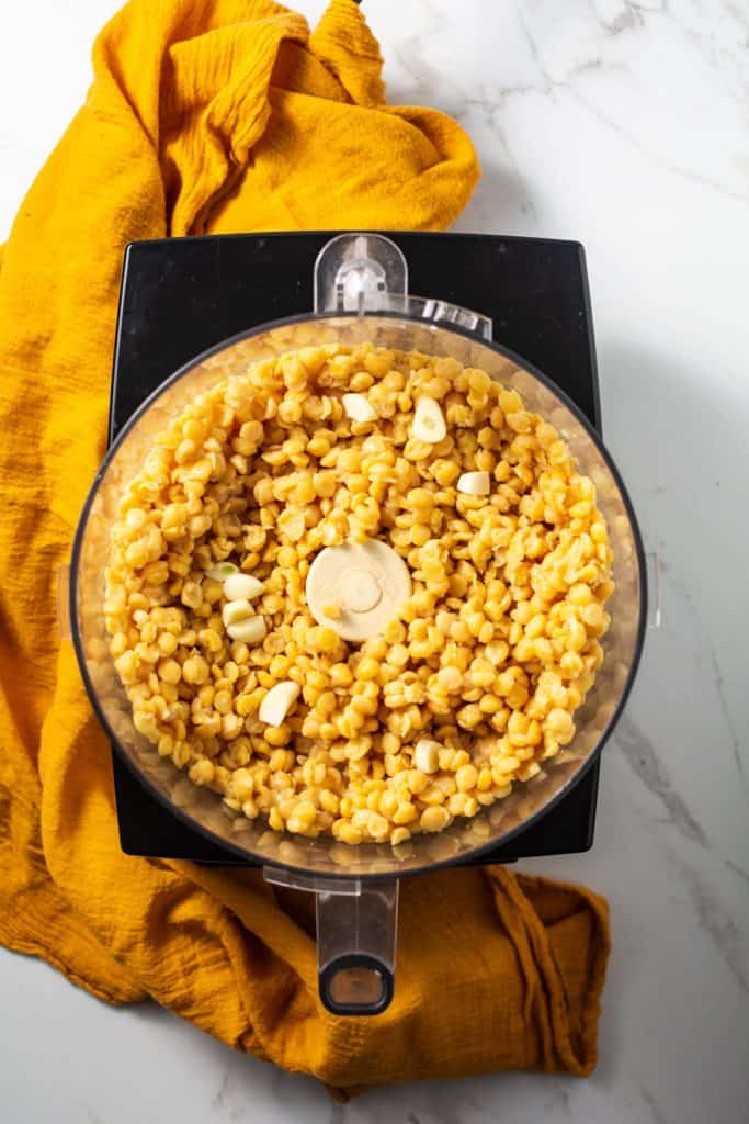 Overhead shot of chana dal and garlic in the food processor.