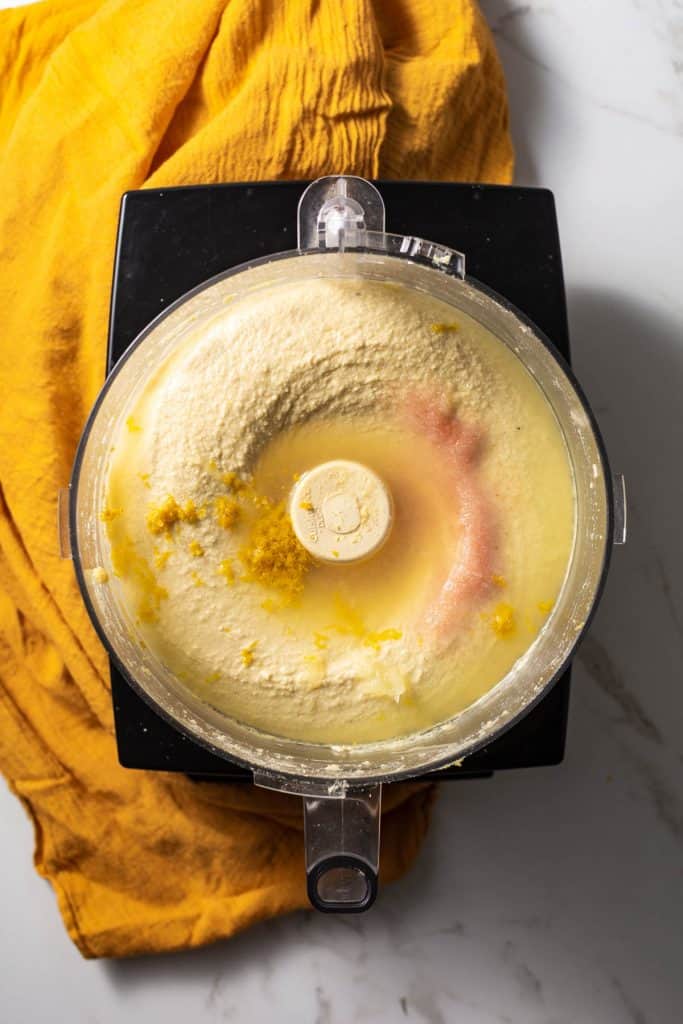 Overhead shot of salt, lemon juice, and zest being added into the food processor.