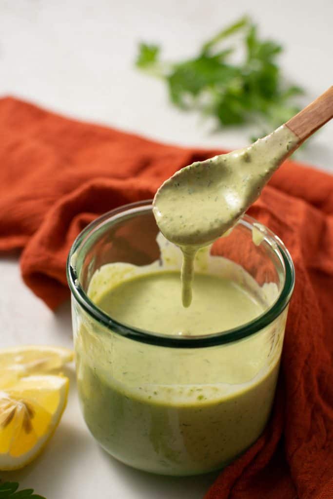 Glass cup of dressing with spoon.