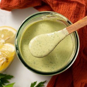 Overhead shot of dressing in glass with wooden spoon.