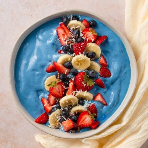 Birdseye view of smoothie bowl with toppings and white towel.