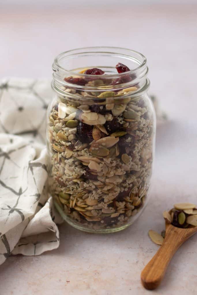 jar full of salad topper mix with wood spoon.