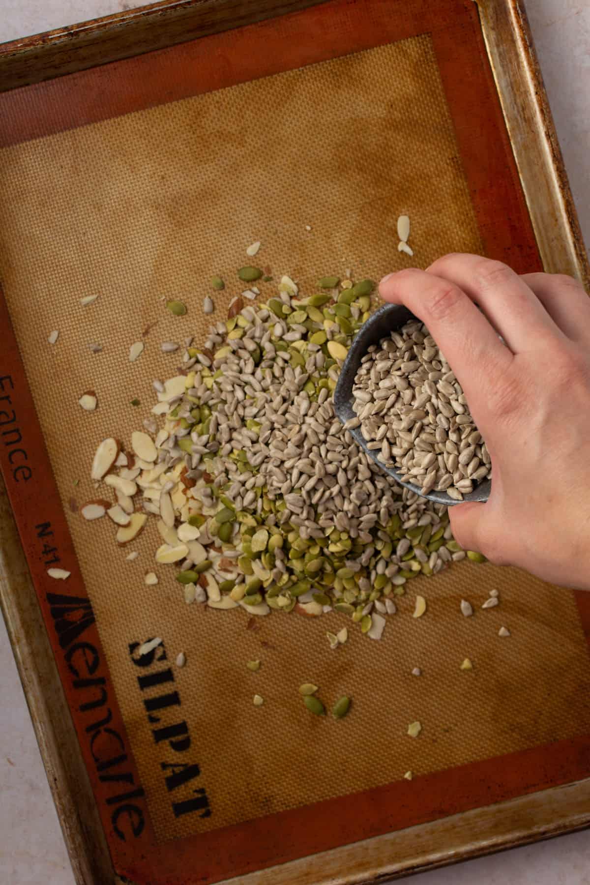 Hand pouring seeds onto cookie sheet.