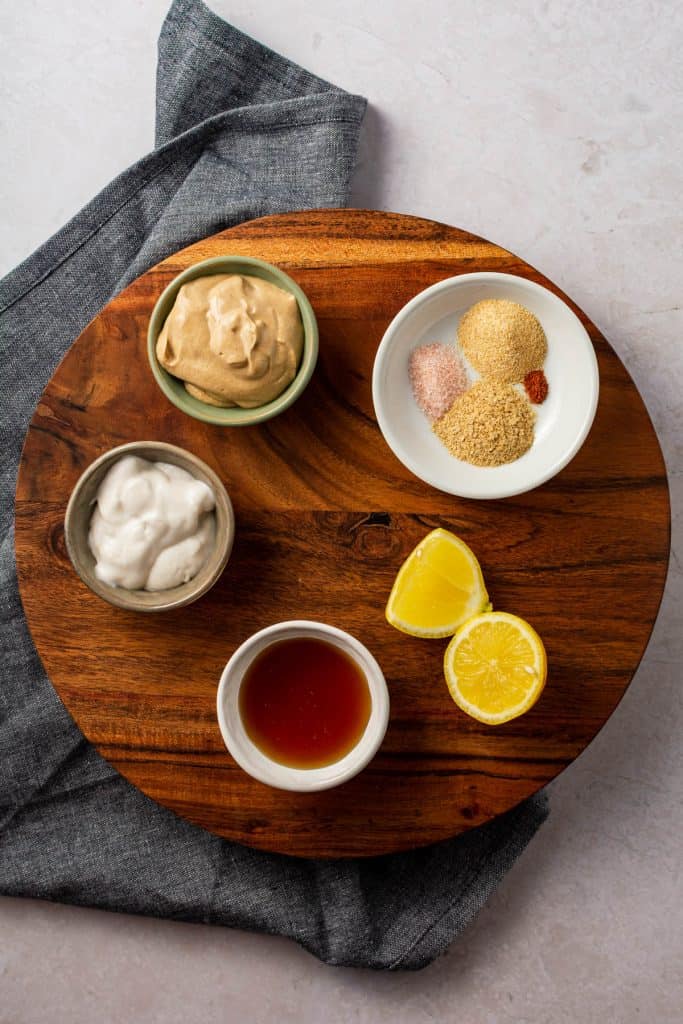 Wood serving bowl with bowls full of separate dressing ingredients.