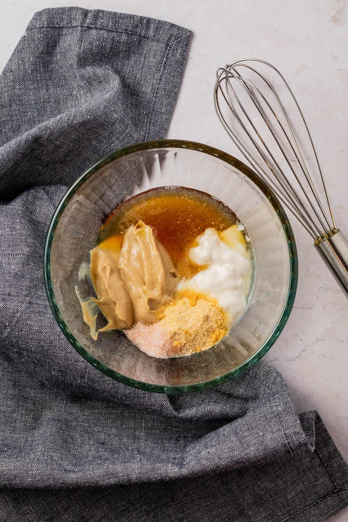 Glass bowl full of dressing ingredients before being mixed together.