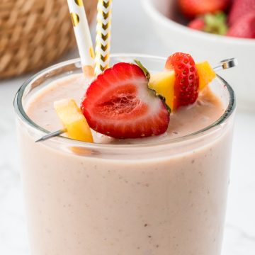 Close of up smoothie with cut fruit on top and fun paper straws.