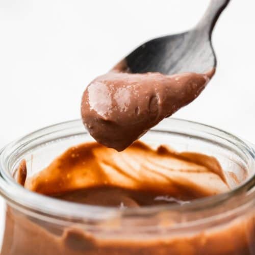 Close up of glass jar of pudding with spoonful coming out.