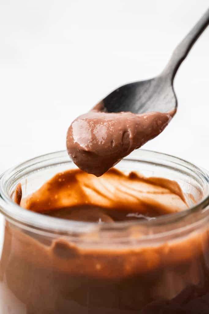 close up of someone taking a spoon full of pudding out of the jar