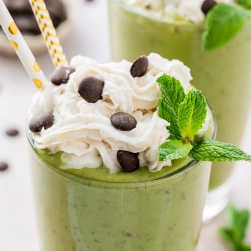 Close up of smoothie with whipped cream and chocolate chips on top.