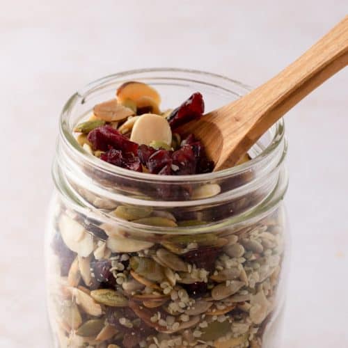 close up of jar full of salad topper mix with wooden spoon sticking out of it.