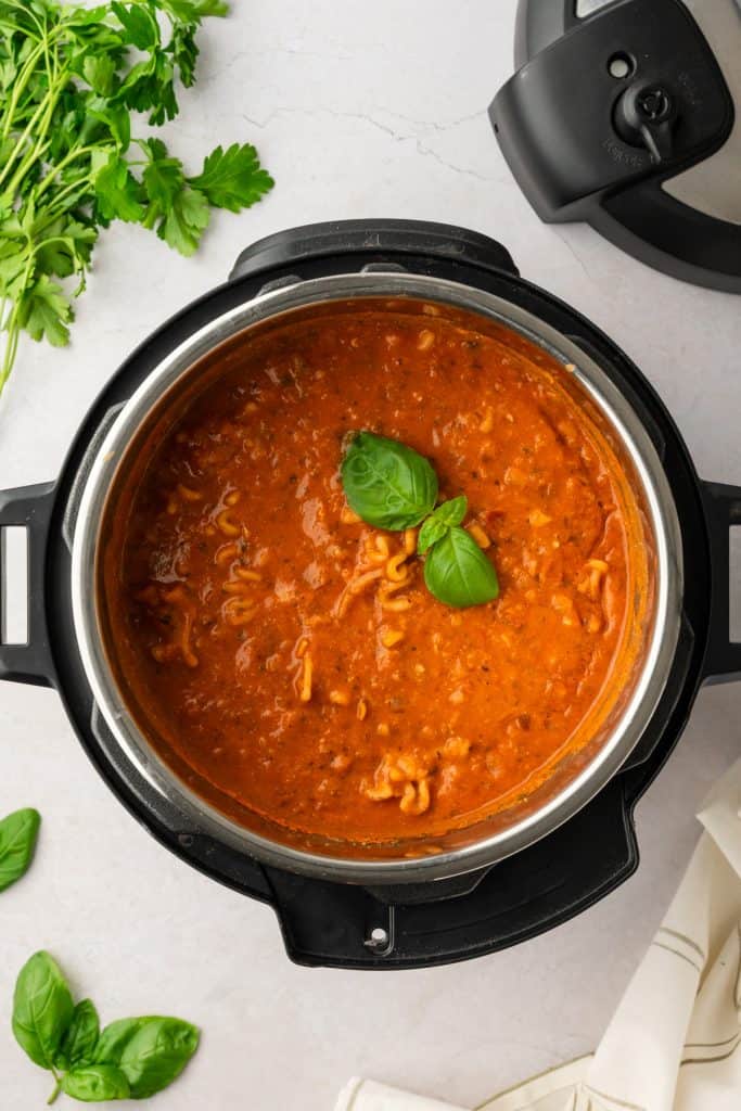 Overhead shot of finished soup in the instant pot. Lid and fresh herbs in the background.