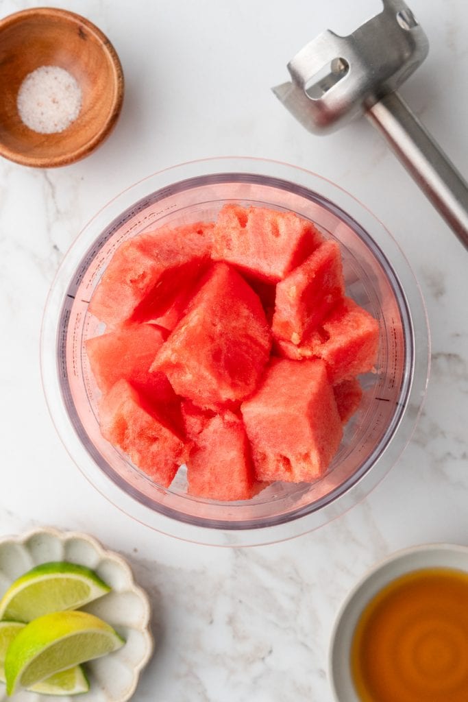 overhead shot of pint container full of watermelon surrounded by salt, lime, maple syrup and immersion blender.