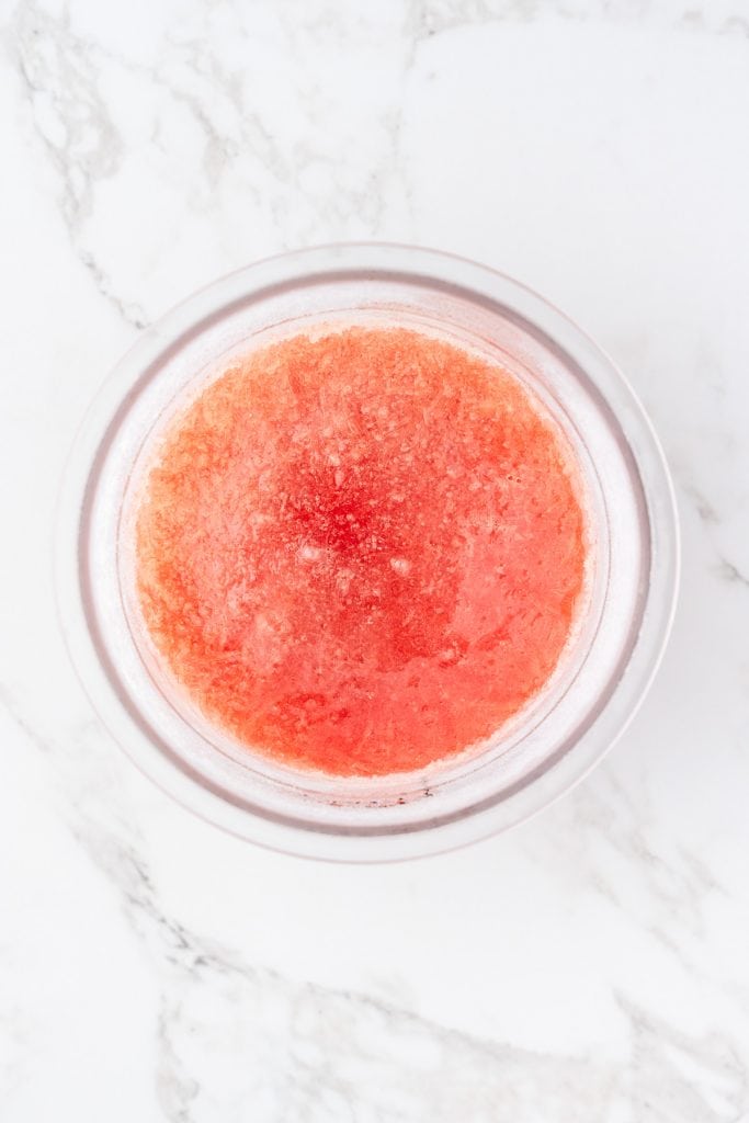 overhead shot of the pint container full of the frozen ingredients for the watermelon sorbet before processing.