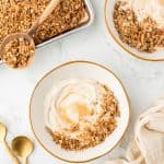 overhead shot of two bowls of yogurt topped with granola. Pan of cooked granola in the corner.