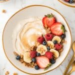 overhead shot of bowl of yogurt topped with berries and granola.