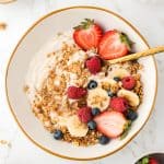 overhead shot of bowl of yogurt topped with berries and granola.