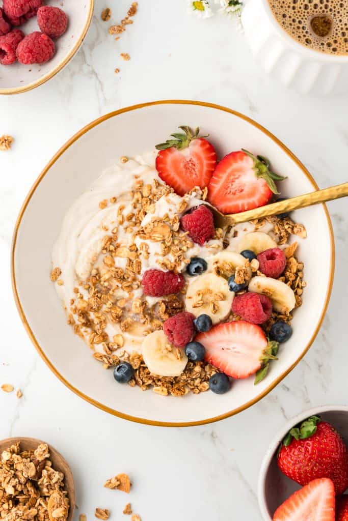 overhead shot of bowl of yogurt topped with berries and granola.