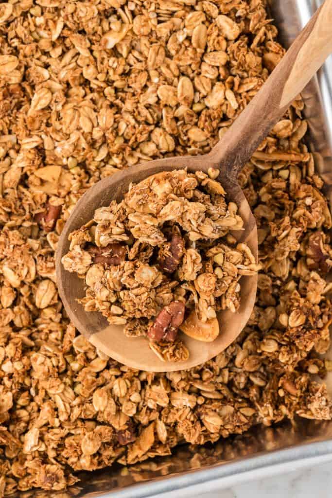 close up overhead shot of granola in pan with a wooden spoon.